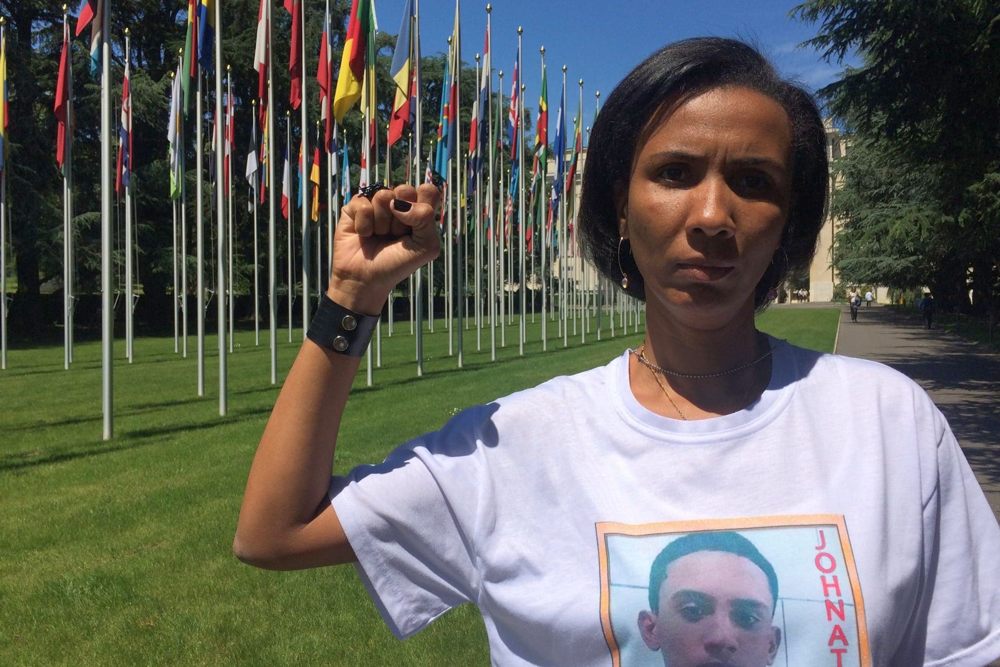 Ana Paula Gomes de Oliveira with her raised fist in front of the UNO building Behind her the flags of the member countries.