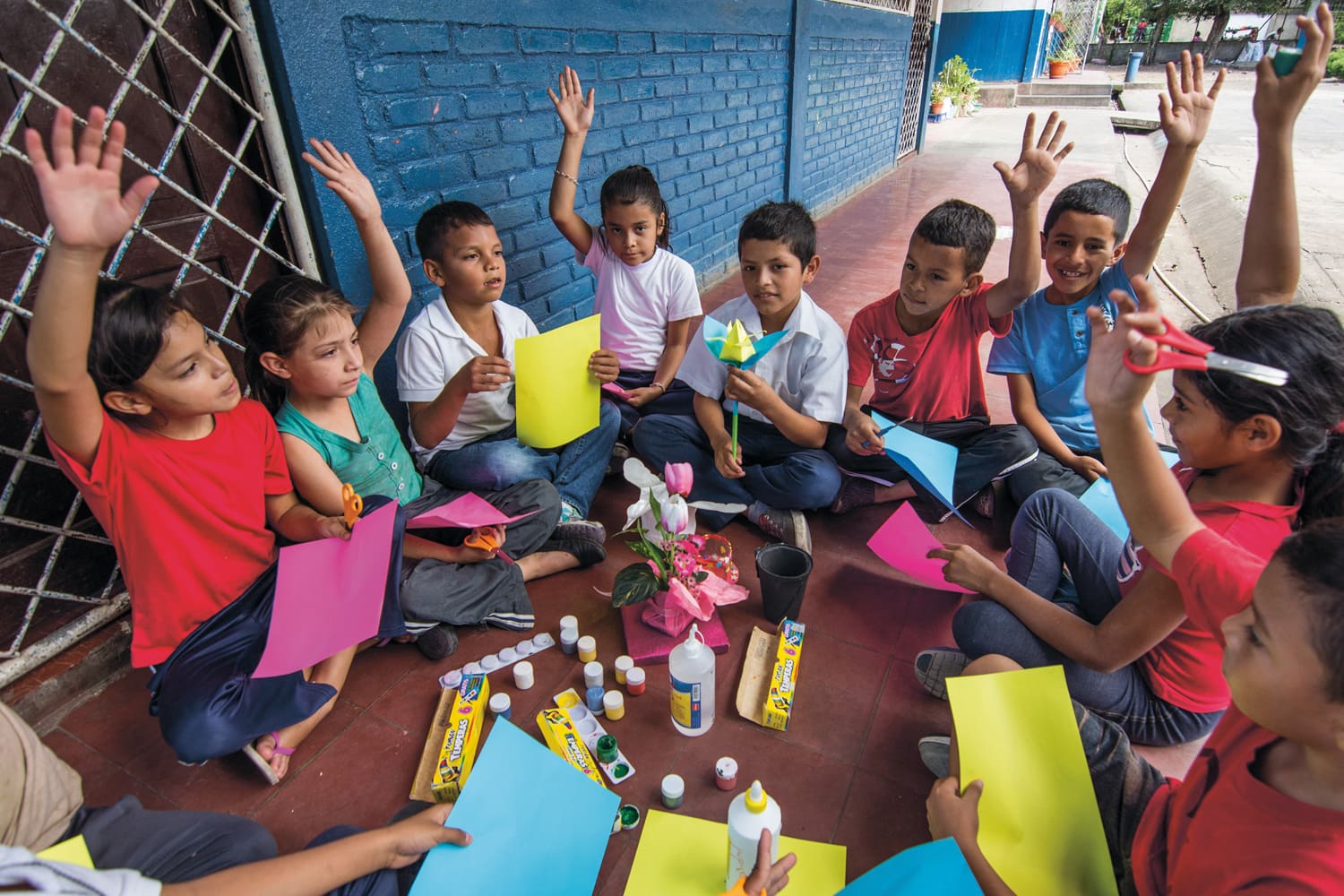 Children sit together in a circle and write or do handicrafts.