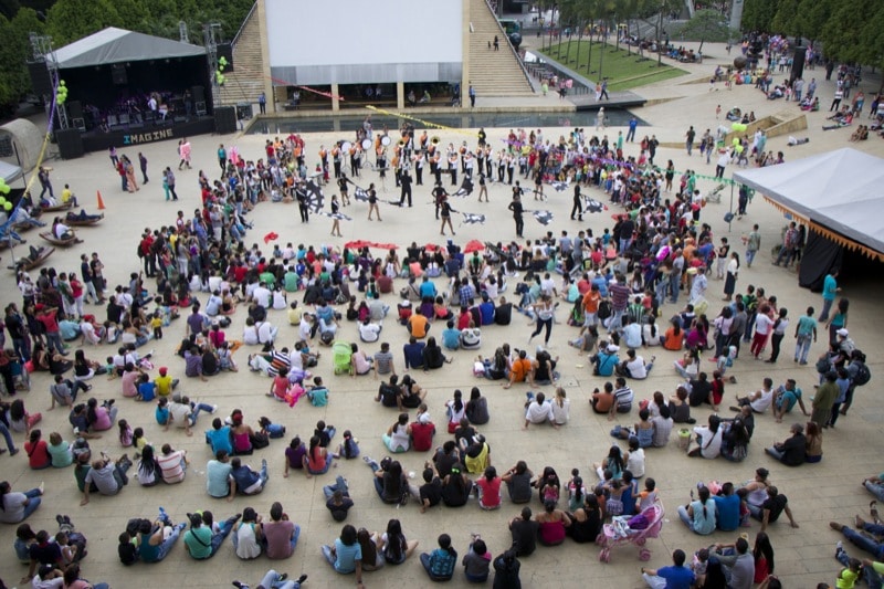 A large square with a stage and it is full of people.