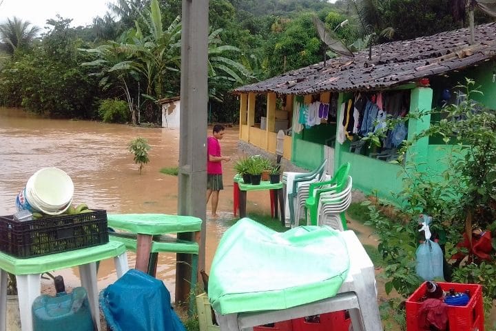 House surrounded by brown floods. Palm trees in the background, garden furniture in the foreground.