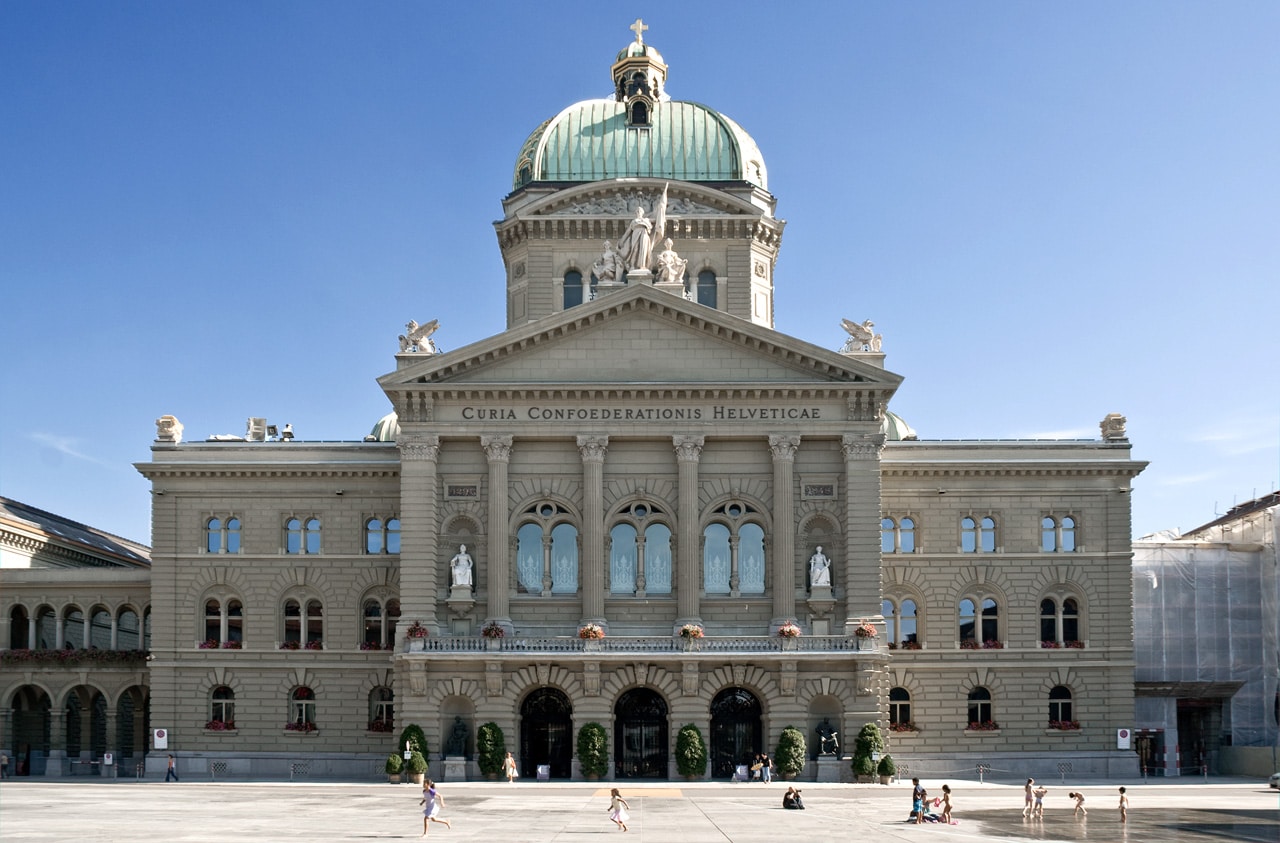 The Bundeshaus in Bern under a cloudless sky. People on the Bundesplatz.