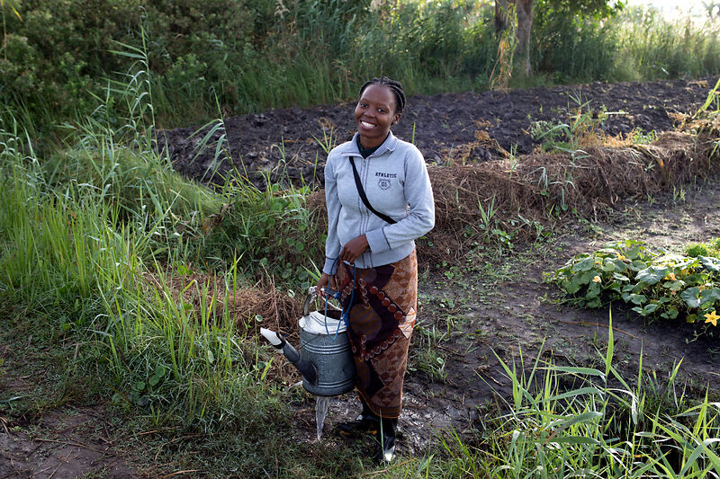 Young woman in a field with a watering can - Project in Mozambique - terre des hommes schweiz