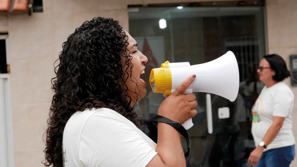 Junge Frau an einer Demonstration mit Megaphon - terre des hommes schweiz